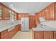 Spacious kitchen featuring wooden cabinetry, white appliances, and tile flooring at 5703 Field St, Arvada, CO 80002