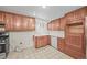 Cozy kitchen featuring wooden cabinets, white appliances, and neutral-toned tiling at 5703 Field St, Arvada, CO 80002