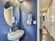 Cozy bathroom featuring a pedestal sink, oval mirror, and dark blue textured walls at 30 Sun Up Ct, Erie, CO 80516