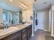 Bathroom with double sinks, granite countertops, a large mirror, and gray tiled floors at 30 Sun Up Ct, Erie, CO 80516