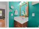 Bright bathroom features a wood vanity, modern mirror, and blue accent wall at 1540 Filbert Ct, Denver, CO 80220