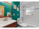 Bright bathroom with turquoise wall, tiled shower over tub, cherry vanity, and modern fixtures at 1540 Filbert Ct, Denver, CO 80220