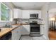 Galley kitchen with white cabinets, butcher block counters, and stainless steel appliances is bathed in natural light at 1540 Filbert Ct, Denver, CO 80220