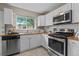 Bright kitchen featuring white cabinets, wood countertops, stainless steel appliances, and a subway tile backsplash at 1540 Filbert Ct, Denver, CO 80220