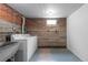 Finished basement laundry room with sink and brick accents on the wall at 1540 Filbert Ct, Denver, CO 80220