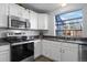 Well-lit kitchen with white cabinets, stainless steel appliances, and a large window at 4633 S Crystal Way # E189, Aurora, CO 80015