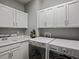 Bright laundry room with white cabinets, modern washer and dryer, and a utility sink with silver fixtures at 2351 Lassen Ln, Castle Rock, CO 80109