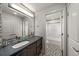 Modern bathroom features gray countertops, dual mirrors, and decorative tile accents and flooring at 1730 W 67Th Ave, Denver, CO 80221