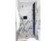 This shower features white marble-patterned tile, bronze hardware, and pebble flooring at 9280 Russell Way, Thornton, CO 80229