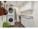 Well-lit laundry room featuring a stacked washer and dryer, plus storage cabinets and counter space at 20182 E Maplewood Pl, Centennial, CO 80016