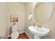 Well-lit half-bathroom featuring a pedestal sink, modern fixtures, and decorative accents at 8421 Galvani Trl # E, Littleton, CO 80129