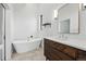 Contemporary bathroom featuring a soaking tub, a modern vanity, stylish mirror, and hexagon tile flooring at 1220 S Elm St, Denver, CO 80246