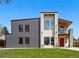 Striking two-story modern home featuring metal and stucco finishes, a balcony, and a bright red front door at 1220 S Elm St, Denver, CO 80246