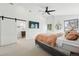 Bright main bedroom with a sliding barn door to the en-suite bathroom, TV, and modern ceiling fan at 1220 S Elm St, Denver, CO 80246