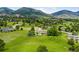 Scenic aerial view of a large property featuring lush green lawns, mature trees, and panoramic mountain vistas at 5586 Colorow Dr, Morrison, CO 80465