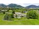Stunning aerial shot showcasing a home on manicured lawns surrounded by mature trees and picturesque mountain views at 5586 Colorow Dr, Morrison, CO 80465