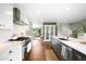 Updated kitchen with stainless steel appliances, grey lower cabinets, and a view to the living room at 5586 Colorow Dr, Morrison, CO 80465