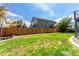 Large fenced backyard with green grass, providing a secure outdoor space with a view of the home's exterior at 6694 E 129Th Ave, Thornton, CO 80602