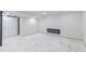 Open basement space with sleek, white marble-style flooring and modern electric fireplace at 6735 W 2Nd Ave, Lakewood, CO 80226