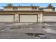 View of garages in a row, each with a tan door and red trim, set on a paved surface with some standing water at 1935 W 102Nd Ave, Thornton, CO 80260