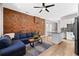 Inviting living area with exposed brick wall, hardwood floors, and cozy blue couch with open concept to the kitchen at 2508 Kensing Ct, Denver, CO 80211