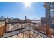 Relax on the rooftop deck with views of the city skyline, a table with chairs, and a wooden railing at 2508 Kensing Ct, Denver, CO 80211