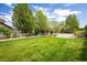 Lush green front lawn with mature trees framing a charming home behind a white picket fence at 2552 Stonewall Ln, Lafayette, CO 80026