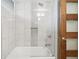Clean bathroom with a white tub, white tile walls, and a wood-framed glass door at 5405 S Lowell Blvd, Littleton, CO 80123