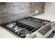 Close-up of a stainless steel gas range with a gray backsplash and white countertops at 20968 E 60Th Pl, Aurora, CO 80019