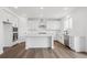 A bright, white kitchen features an island with modern stainless appliances and finishes at 7016 E 126Th Pl, Thornton, CO 80602