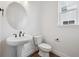 Well-lit powder room featuring a pedestal sink, modern toilet, and a wall mirror at 7016 E 126Th Pl, Thornton, CO 80602