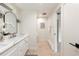 Updated bathroom with a double sink vanity, framed mirror, modern lighting, and tile floors at 7453 E Jefferson Dr, Denver, CO 80237