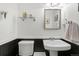 Neat bathroom with pedestal sink, decorative mirror, and sleek black and white wainscoting at 11936 W Temple Dr, Morrison, CO 80465