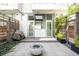 Private patio featuring modern design with a fire pit, stone pavers, lush green plants, and building facade at 1467 Delgany St # 1, Denver, CO 80202