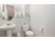 Well-lit half bathroom features a modern pedestal sink, toilet, and a round mirror at 17217 E Exposition Dr, Aurora, CO 80017