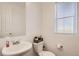 Cozy half-bathroom featuring a sink, toilet, mirror, and window at 5332 13Th St, Frederick, CO 80504