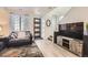 Bright living room featuring light wood floors, a modern door, staircase, and an entertainment center at 5332 13Th St, Frederick, CO 80504