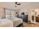 This bedroom features a ceiling fan, a dresser with decor, and a view of the front yard through a large window at 3026 W Prentice Ave # G, Littleton, CO 80123