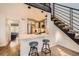 Kitchen with a bar and seating adjacent to a staircase and view into a bedroom at 3026 W Prentice Ave # G, Littleton, CO 80123