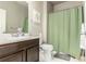 Bathroom with a wooden vanity, white countertop and toilet, and a green shower curtain at 697 Gamble Oak St, Brighton, CO 80601