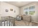Cozy Bedroom with a crib, comfortable armchair, dresser, and natural light, creating a peaceful and inviting space at 697 Gamble Oak St, Brighton, CO 80601