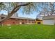Well-maintained backyard with a mix of lawn and mature trees, complemented by a brick house exterior at 1359 S Brentwood Way, Lakewood, CO 80232