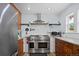 Stainless steel range with custom hood and overhead pot rack in updated kitchen at 1359 S Brentwood Way, Lakewood, CO 80232