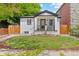 Charming white brick home with green door, black trim, and a well-manicured lawn and landscaping at 1845 W 39Th Ave, Denver, CO 80211