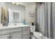 This bright bathroom features a large single sink vanity and a gray shower curtain at 21492 E 60Th Ave, Aurora, CO 80111