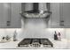 Modern kitchen featuring a gas cooktop, stainless steel hood, and elegant backsplash at 21492 E 60Th Ave, Aurora, CO 80111