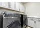 This updated laundry room features modern, high-end washer and dryer units and bright white cabinets at 21492 E 60Th Ave, Aurora, CO 80111