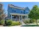 Charming blue two-story home featuring a covered front porch and solar panels on the roof at 5514 Uinta St, Denver, CO 80238