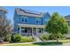 Beautiful blue home featuring solar panels on the roof, a covered porch, and lush landscaping at 5514 Uinta St, Denver, CO 80238