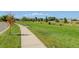 A park-like setting with a concrete walking path and a bench surrounded by green grass and trees at 5514 Uinta St, Denver, CO 80238